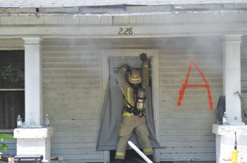 (1) Here, a firefighter deploys a portable door to control air track movement.