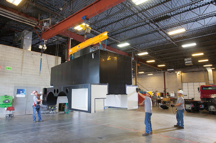 Workers are using an overhead crane to move an All-Poly body. More than 99 percent of Midwest’s production is with high-impact-resistant copolymer polypropylene.