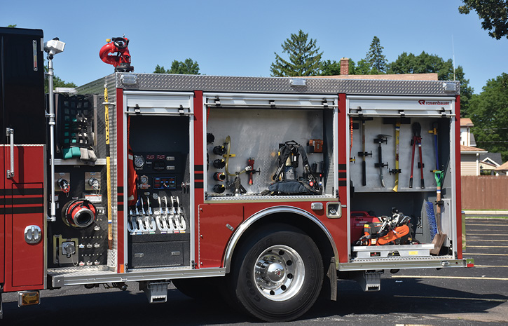 The driver’s side narrow pump panel and large compartments with engine company fittings, forcible entry tools, and saw.