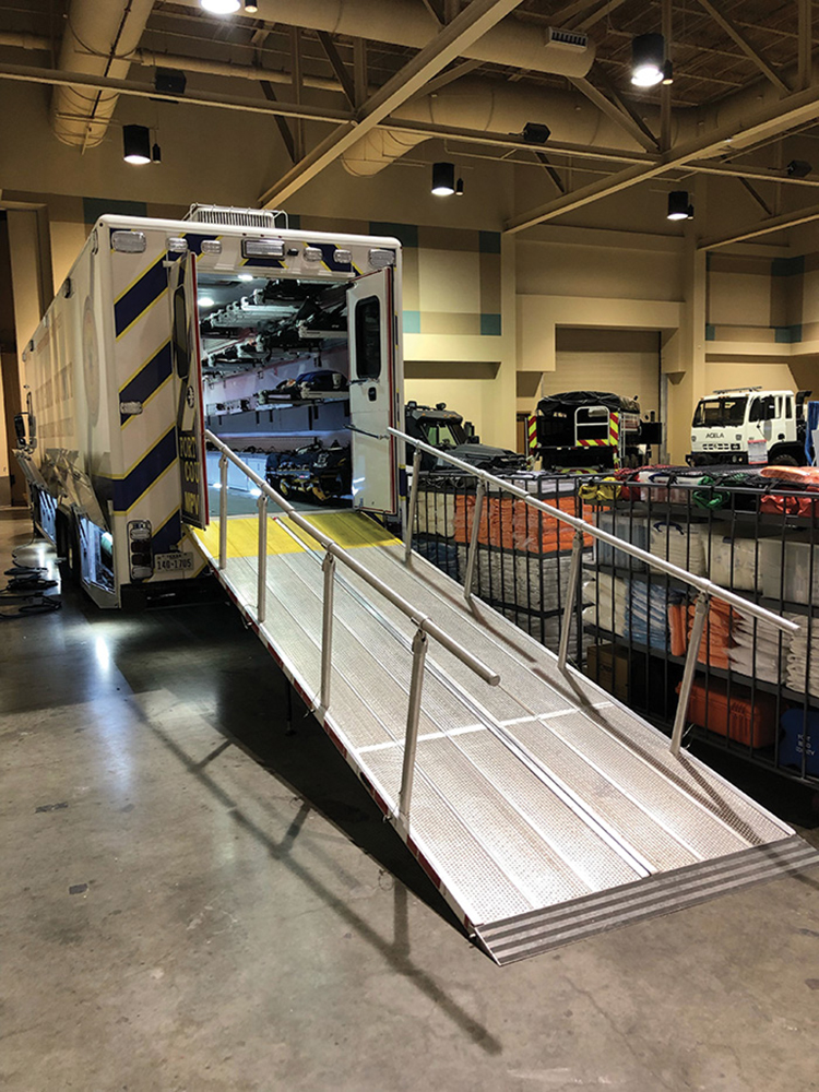 A large, bifold ramp with detachable hand rails stowed in between the rear truck frame rails provides access to an oversized rear door. A special transition plate bridges the apparatus and facility loading docks to make it easier to load entire hospital beds into the rear of the unit.