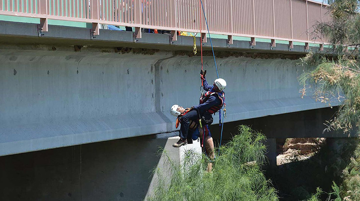 A Northwest (AZ) Fire District  firefighter pulls a simulated victim from a swift water situation after rappelling off a bridge to reach the victim. (Photos 3-4 courtesy of Northwest Fire Department.)