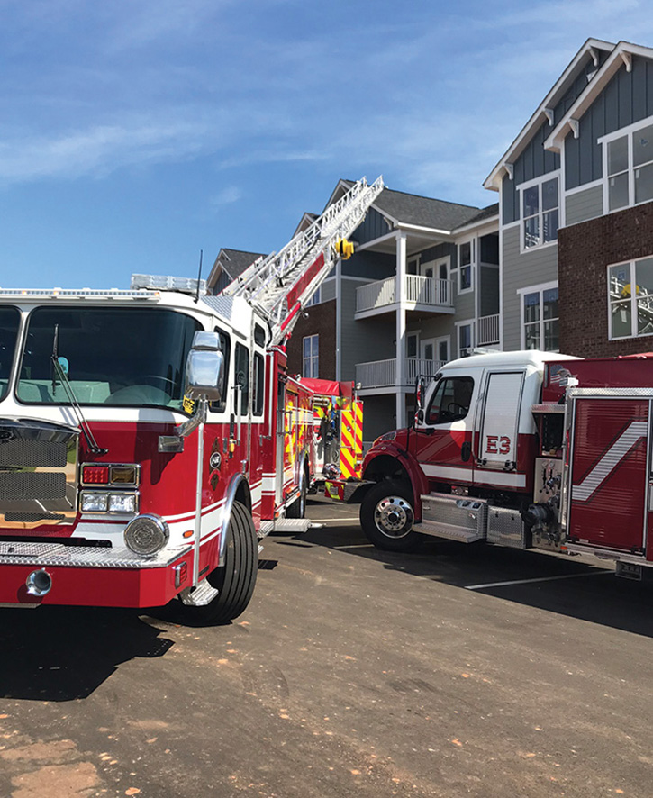 An E-ONE HP78 aerial ladder sets up in tight quarters at a housing complex.