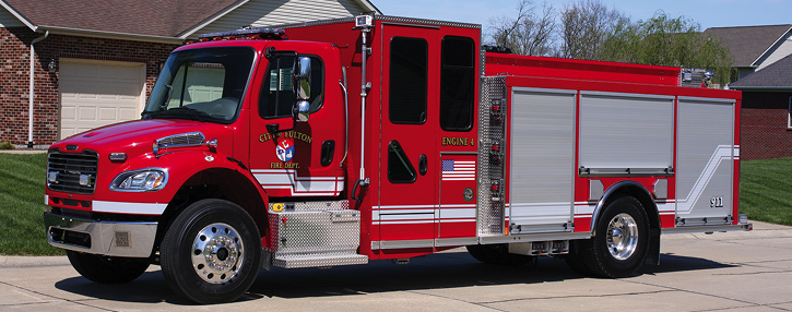 The Fulton (MO) Fire Department operates an all-red two-door Freightliner with a standalone Rosenbauer Smart Cab, 1,500-gpm rear-mount pump, 750-gallon tank, and unpainted roll-up doors.