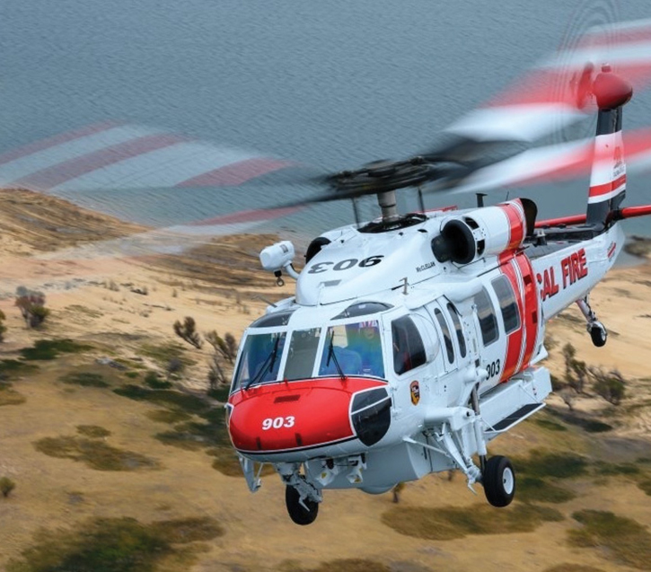 A CAL FIRE twin-engine UH-1H Huey sizes up a wildland fire’s perimeter.