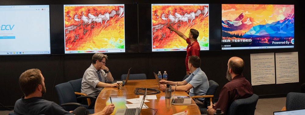 Kyle Thiem, test and evaluation meteorologist with NOAA's Global Systems Laboratory, highlights a high wind event in an upcoming simulation at the start of the final day of evaluating two new wildland fire decision support tools in NOAA’s new Fire Weather Testbed. Alex Zwink, left, an IT specialist with the NWS Warning Decision Training Division, and Michael Pavolonis, center, the Wildland Fire Program manager, look on. (Lauren Lipuma/CIRES/NOAA/TNS)